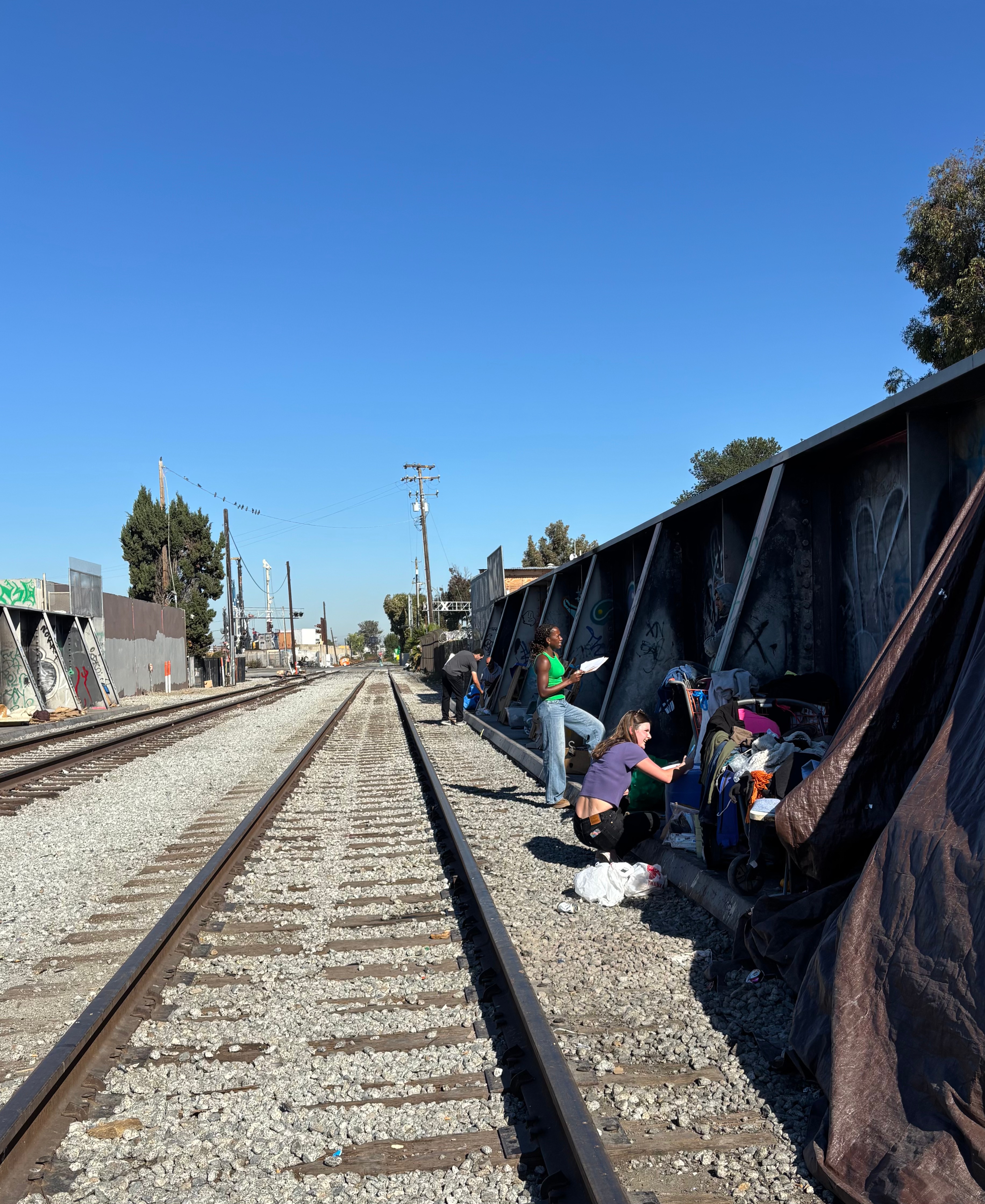 A student speaks to a resident of a homeless encampment adjacent to railroad tracks.