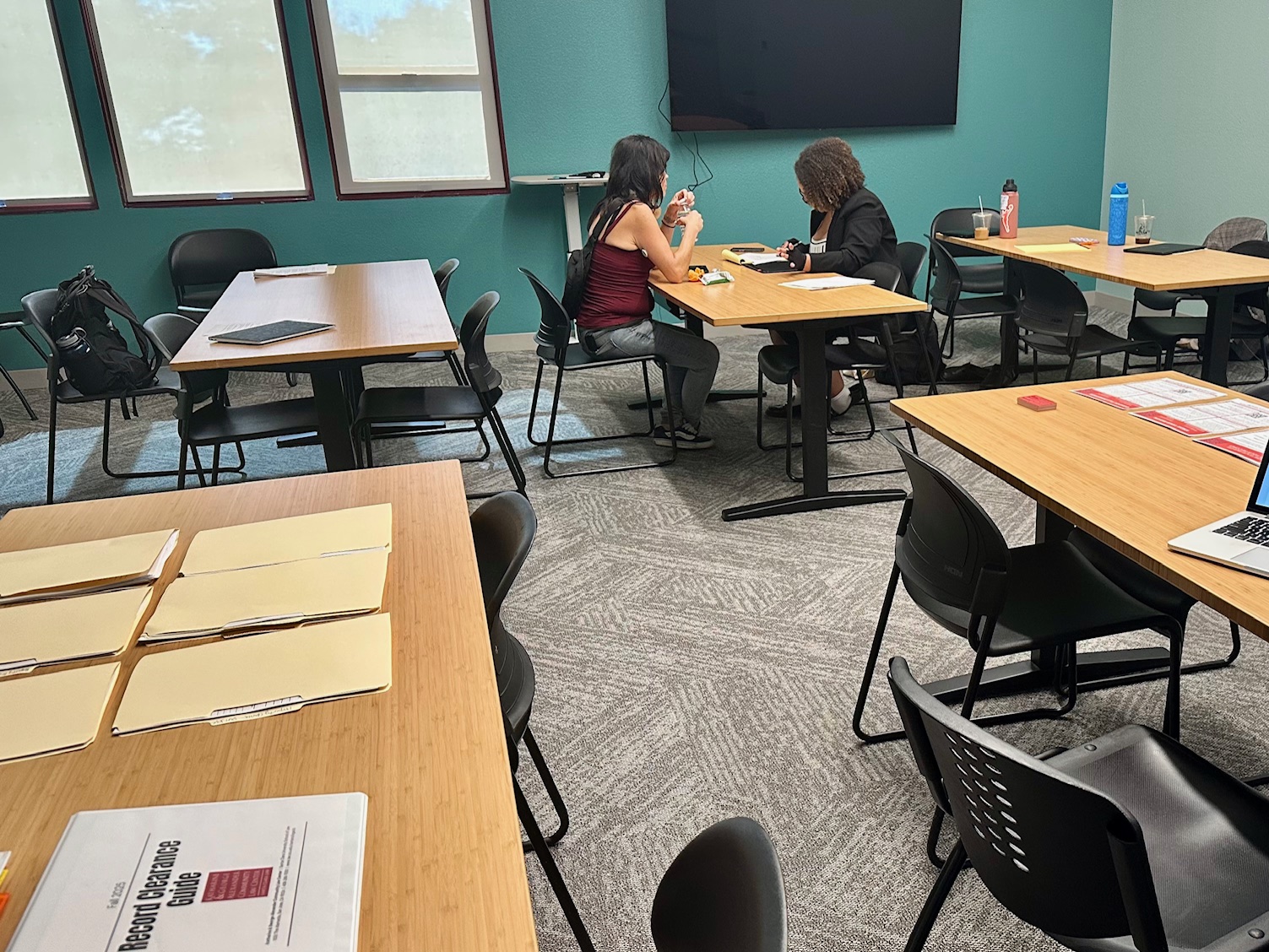 A law student meets with  a client in a room with multiple tables.